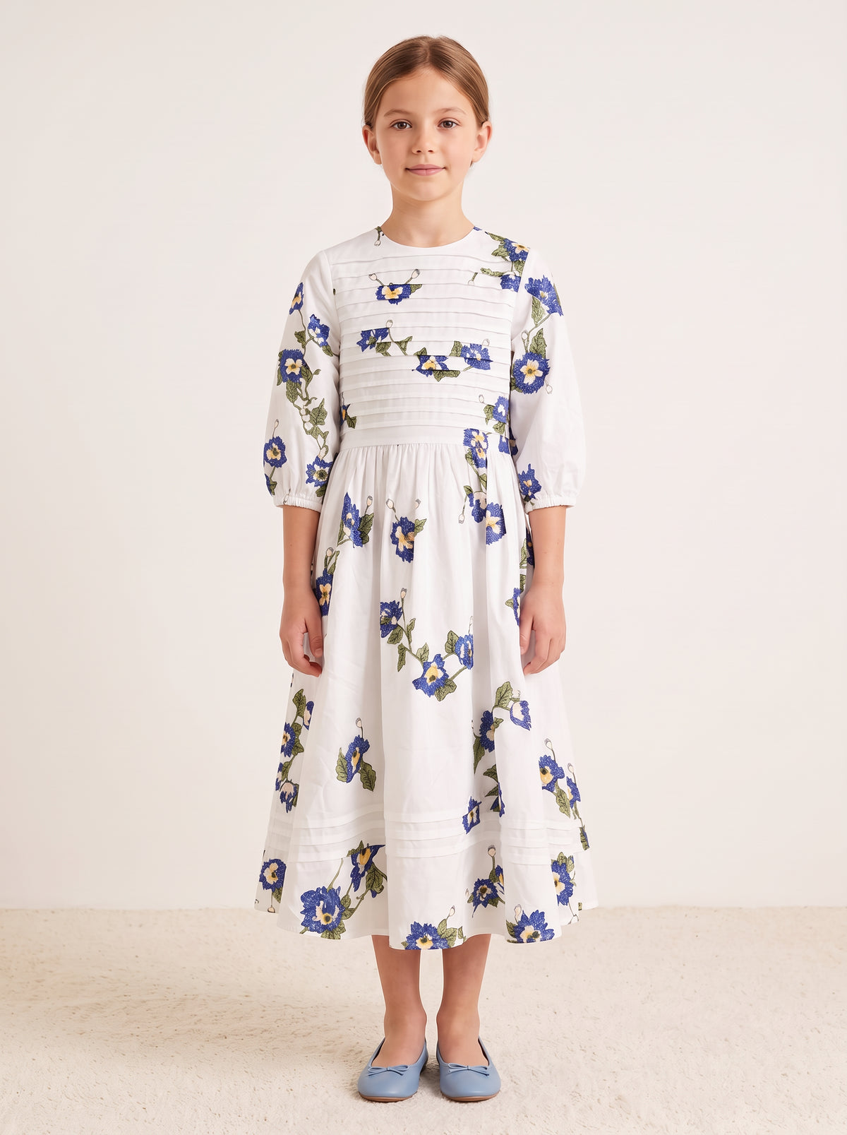 Blue floral pintuck dress on a girl, knee-covering skirt