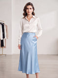 Off-white satin button-down blouse styled with blue satin midi skirt